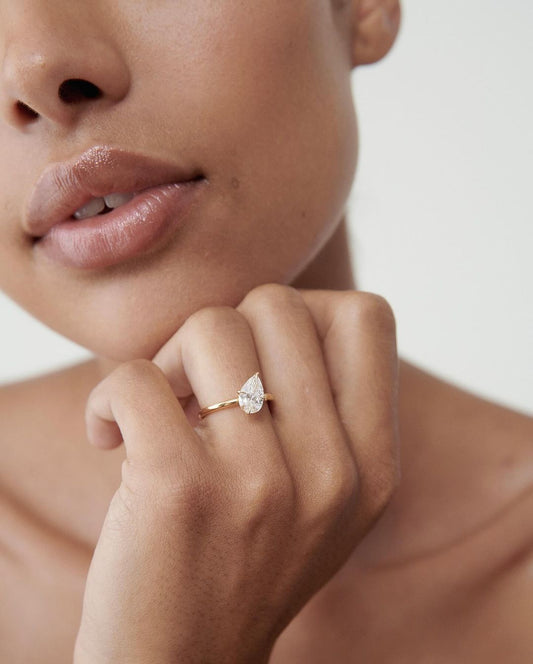 2.5ct Pear Cut Diamond Solitaire Lab Grown Diamond Ring Classic Minimalist Engagement Ring and wedding gift or promise Gift her/women Close-up of a hand adorned with a sparkling diamond ring on a sleek gold band, featuring a modern and elegant design. The ring is perfect for engagement, wedding, or luxury jewelry collections.