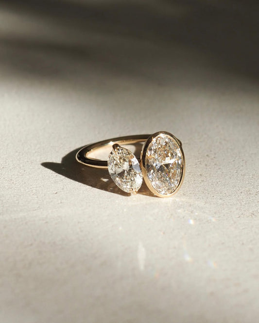 1.5ct Duet Oval Full Bezel Diamond Ring Toi et Moi  The hand displays a soft, natural manicure, highlighting the diamond's brilliance and the ring's refined craftsmanship. Ideal for those seeking timeless, high-end accessories for special occasions.  The hand displays a soft, natural manicure, highlighting the diamond's brilliance and the ring's refined craftsmanship. Ideal for those seeking timeless, high-end accessories for special occasions.