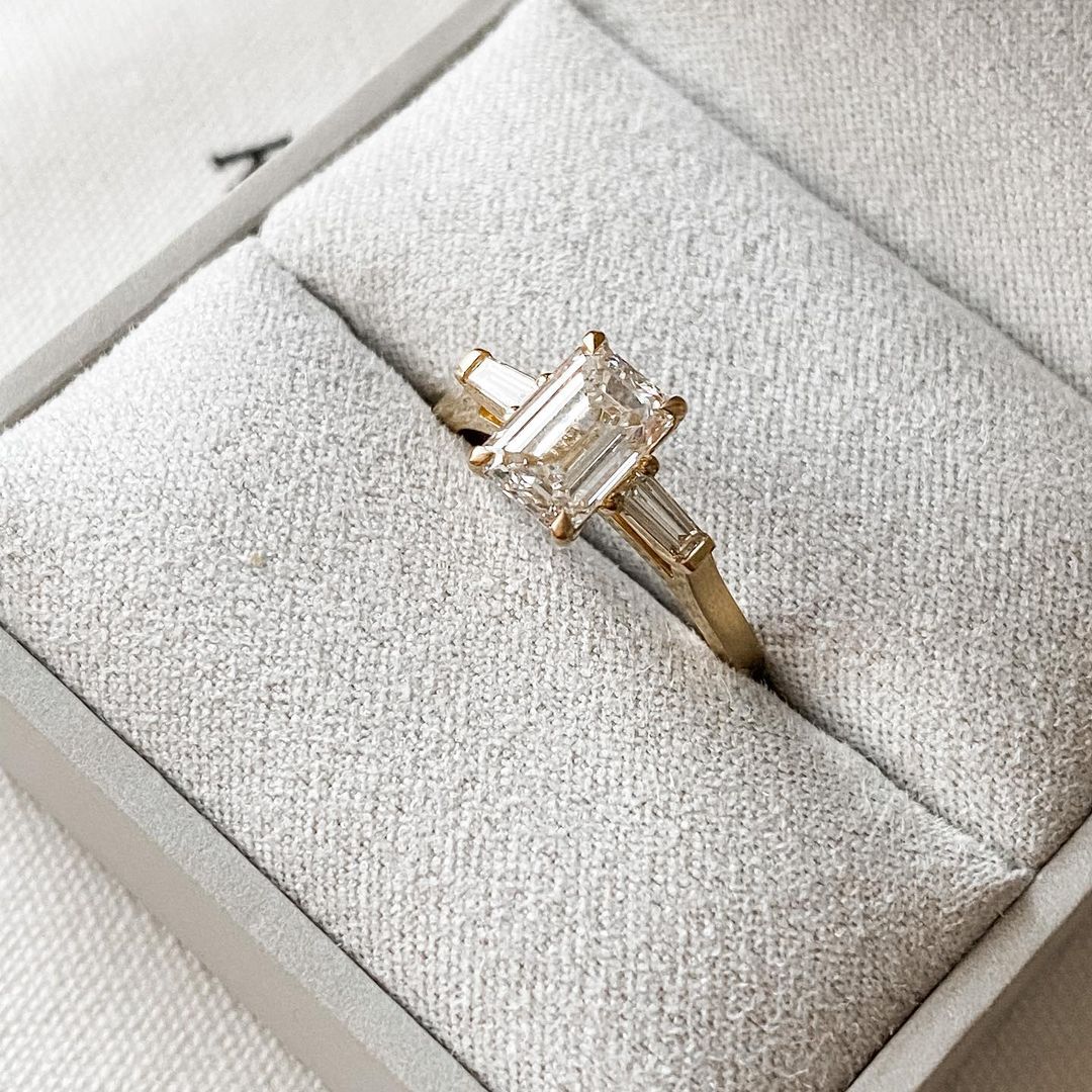 2.5ct Emerald Center Stone With Two Side Baguette Stone Lab Grown Diamond Ring Minimalist  diamond ring on a gold band, symbolizing timeless elegance, showcased on a naturally manicured hand. diamond ring, gold engagement ring, luxury bridal jewelry  and anniversary diamond ring
