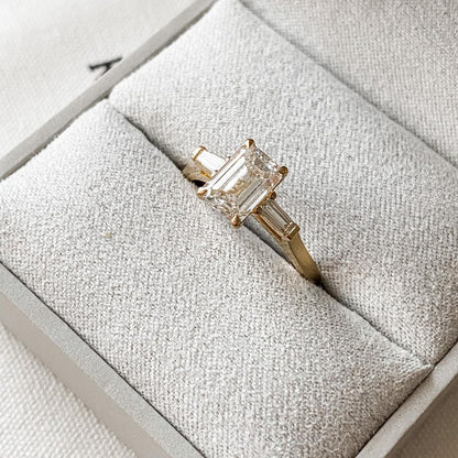 2.5ct Emerald Center Stone With Two Side Baguette Stone Lab Grown Diamond Ring Minimalist  diamond ring on a gold band, symbolizing timeless elegance, showcased on a naturally manicured hand. diamond ring, gold engagement ring, luxury bridal jewelry  and anniversary diamond ring